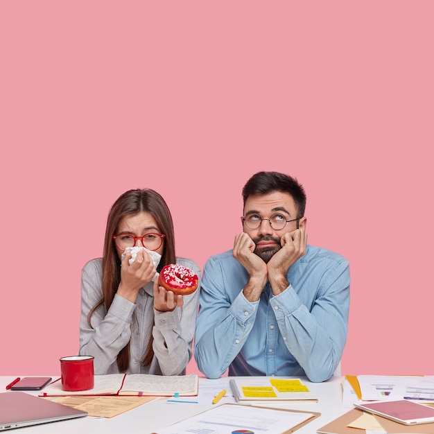 Coworkers sitting at desk with documents and gadgets