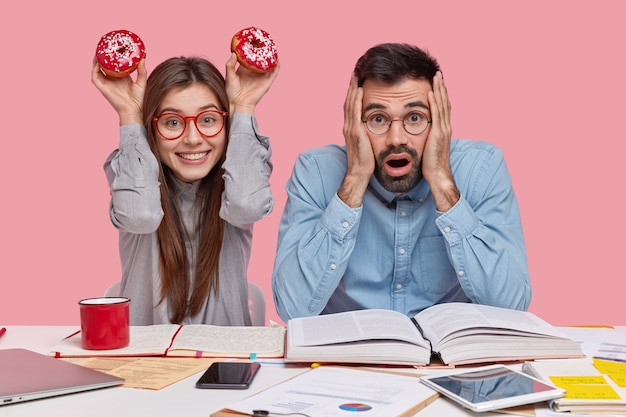 Coworkers sitting at desk with documents and gadgets