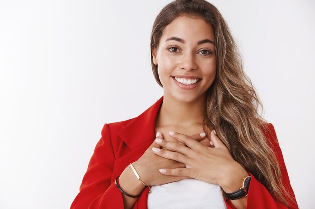 Coworkers throw party congratulating woman accomplishment. Portrait surprised grateful satisfied happy young attractive female pressing palms chest thankful smiling upbeat, white wall