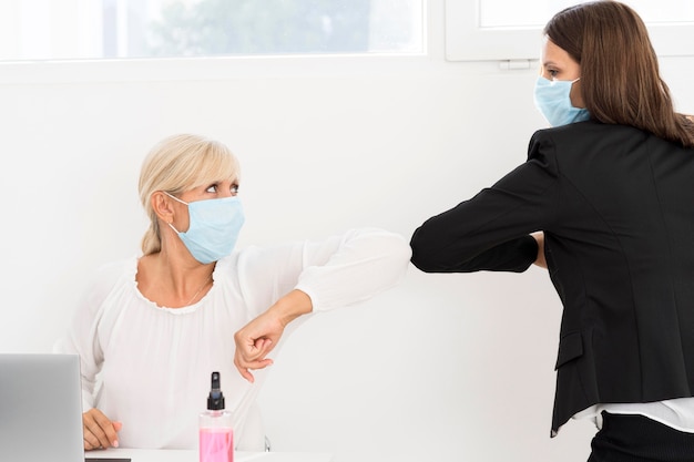 Coworkers wearing masks and elbow bump each other