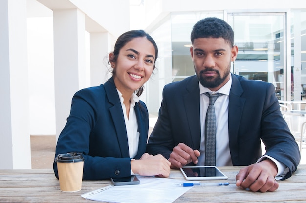 Coworkers working at office desk with tablet, papers and coffee