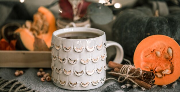 一杯のお茶とカボチャの暖かい居心地の良い秋の静物、暖かい格子縞のシナモンスティック、秋または冬のシーズンのコンセプト