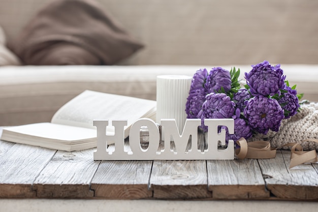 Free photo cozy background with decorative word home, chrysanthemum bouquet, book and candle.