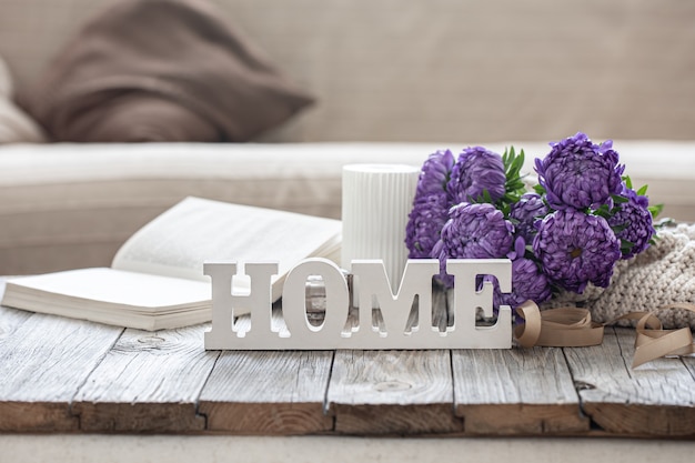 Cozy background with decorative word home, chrysanthemum bouquet, book and candle.