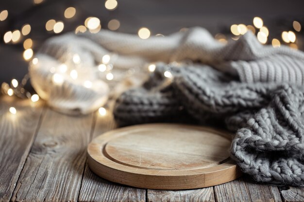 Cozy background with knitted element on a wooden element and bokeh lights