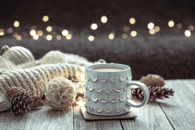 Уютный новогодний фон с красивой чашкой и деталями декора на размытом фоне с боке.