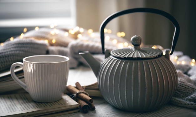 Бесплатное фото Уютная композиция с чайником, чашкой и книгой на размытом фоне