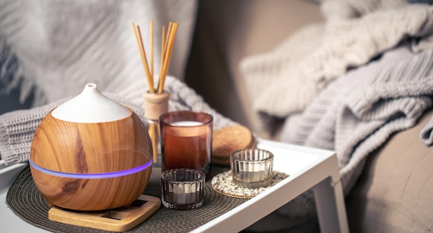 A cozy composition with an aroma diffuser and candles in a home interior