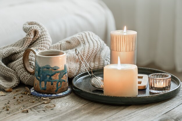 Cozy composition with a ceramic cup, candles and a knitted element