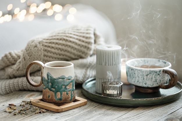 Free photo cozy composition with ceramic cups and candles on a blurred background with bokeh.