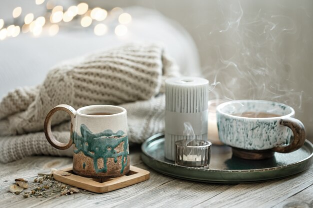 Cozy composition with ceramic cups and candles on a blurred background with bokeh.