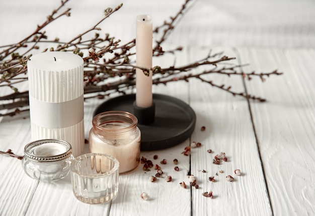 Cozy composition with decorative candles and young tree branches on a wooden surface in a rustic style.