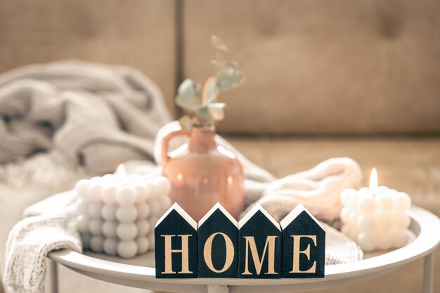cozy composition with decorative word home candles and vase on blurred background