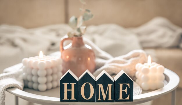 cozy composition with decorative word home candles and vase on blurred background