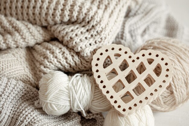 Cozy composition with knitted items and a wooden decorative heart close up.