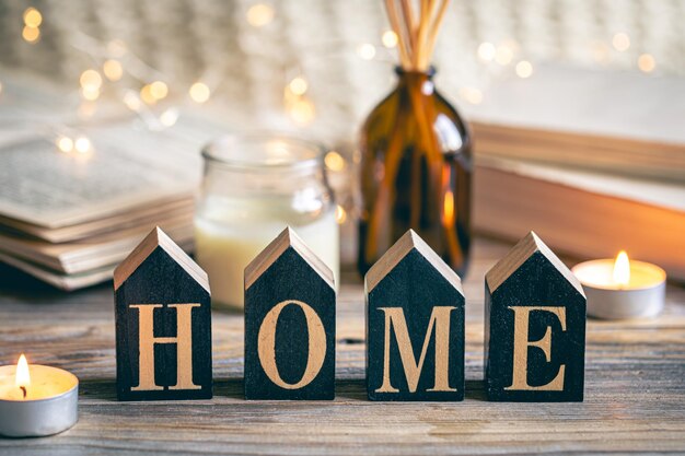 Free photo cozy composition with wooden word home and candles on a blurred background