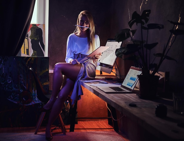 At the cozy dark loft attractive student is sitting on the table while studying.