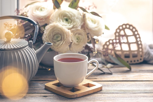 Бесплатное фото Уютная домашняя композиция с чашечкой чая и цветами