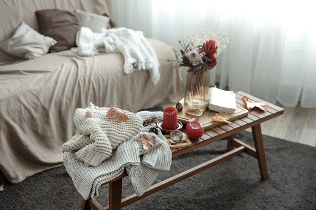 A cozy home composition with candles a book knitted sweaters and leaves