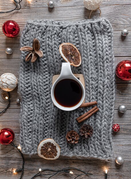 Cozy home composition with a cup of tea on a knitted element, details of christmas decor, flat lay.