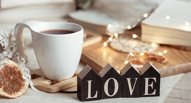 Cozy home composition with decorative word love on blurred background with bokeh.