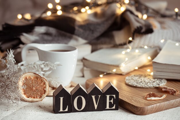 Cozy home composition with decorative word love on blurred space with bokeh.