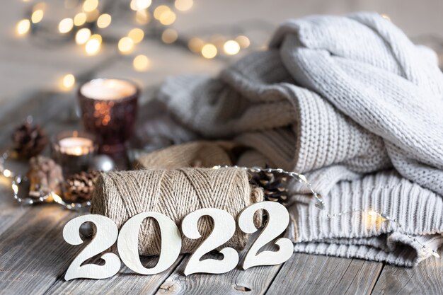 Уютная новогодняя композиция с декоративными числами 2022, вязанными элементами и боке.