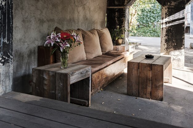 cozy outdoor bench with pillows and a table