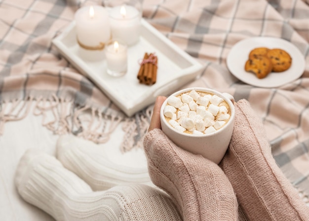 Cozy person holding mug with hot cocoa and marshmallows