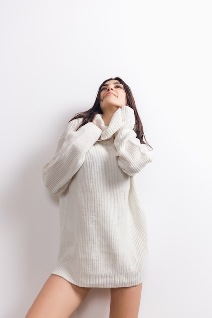 Cozy. Portrait of beautiful brunette woman in comfortable soft long sleeve isolated on white  wall. Home comfort, emotions, facial expression, winter mood concept. Copyspace.