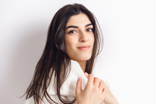 Cozy. Portrait of beautiful brunette woman in comfortable soft long sleeve isolated on white  wall. Home comfort, emotions, facial expression, winter mood concept. Copyspace.