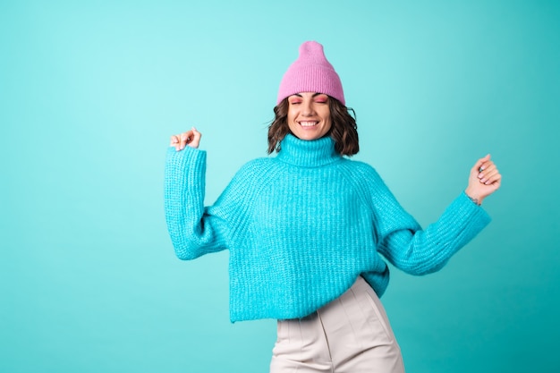 Cozy portrait of a young woman in a knitted blue sweater and a pink hat with bright makeup