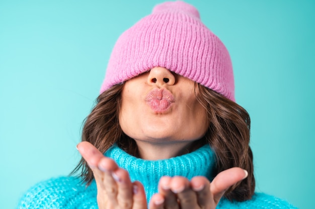 Cozy portrait of young woman in knitted blue sweater and pink hat