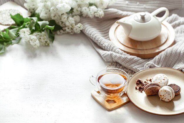 一杯のお茶、ティーポット、フレンチマカロン、ライラック色の居心地の良い春の組成物