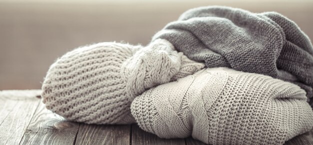 A cozy stack of knitted sweaters on a wooden table