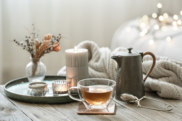 Free photo cozy still life with a glass cup of tea, a teapot and candles