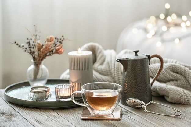 Cozy still life with a glass cup of tea, a teapot and candles