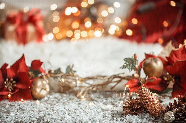 Cozy winter christmas wall with snow and decorative pine cones on blurred colorful wall.