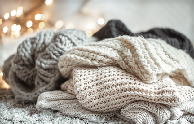 Cozy winter composition with knitted items on a blurred background with bokeh.