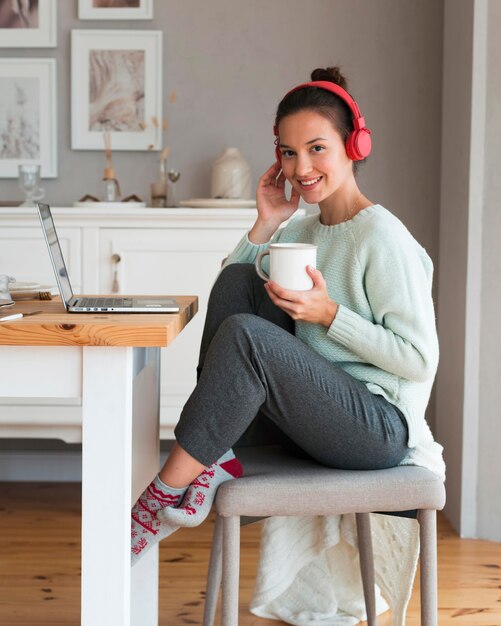 Cozy woman holding mug and sitting on chair