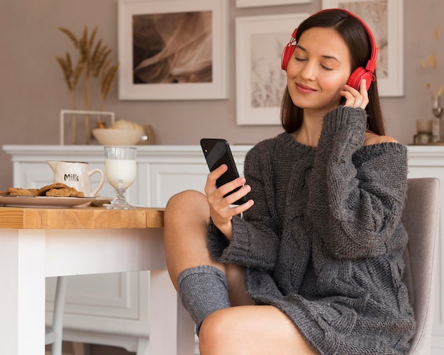 Foto gratuita accogliente donna seduta su una sedia e ascoltare musica