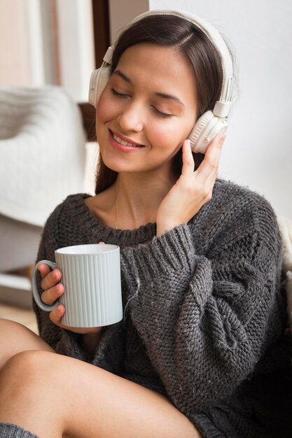 音楽を聴いているマグカップと居心地の良い女性