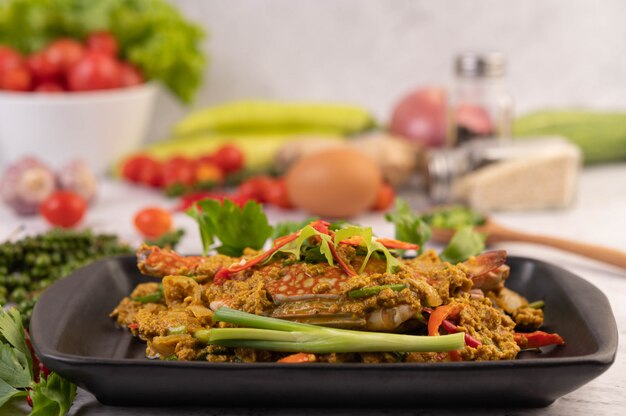 Crab stir-fried curry powder on a black plate on the cement floor.