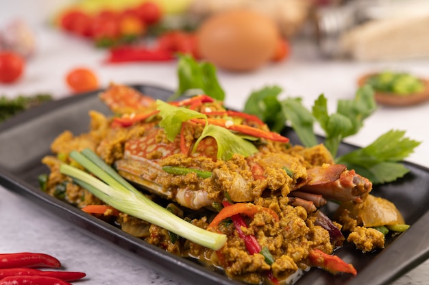 Crab stir-fried curry powder on a black plate on the cement floor.