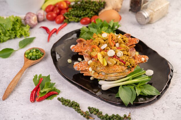 Crab stir-fried curry powder on a black plate on the cement floor.