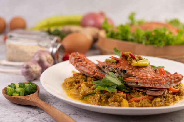 Crab stir-fried curry powder on a white plate on the cement floor.