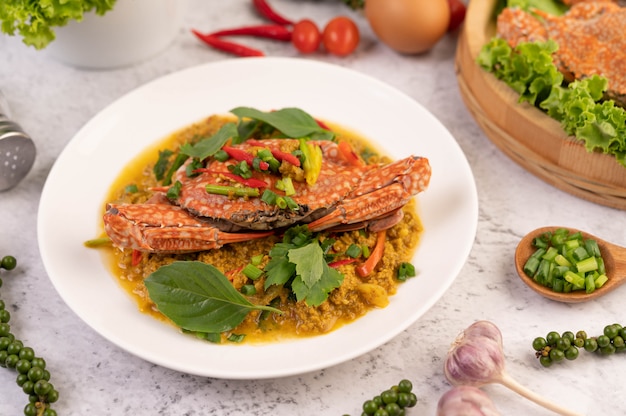 Crab stir-fried curry powder on a white plate on the cement floor.