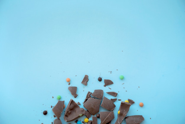 Бесплатное фото Треснувший шоколад с конфетами на синем столе