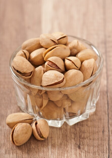 Cracked and dried pistachio nuts in a wooden bowl