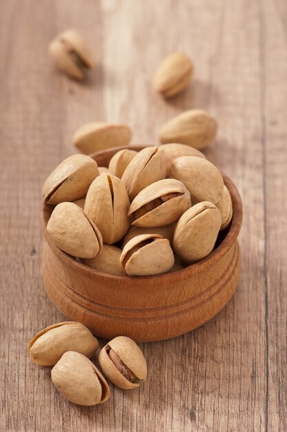 Cracked and dried pistachio nuts in a wooden bowl